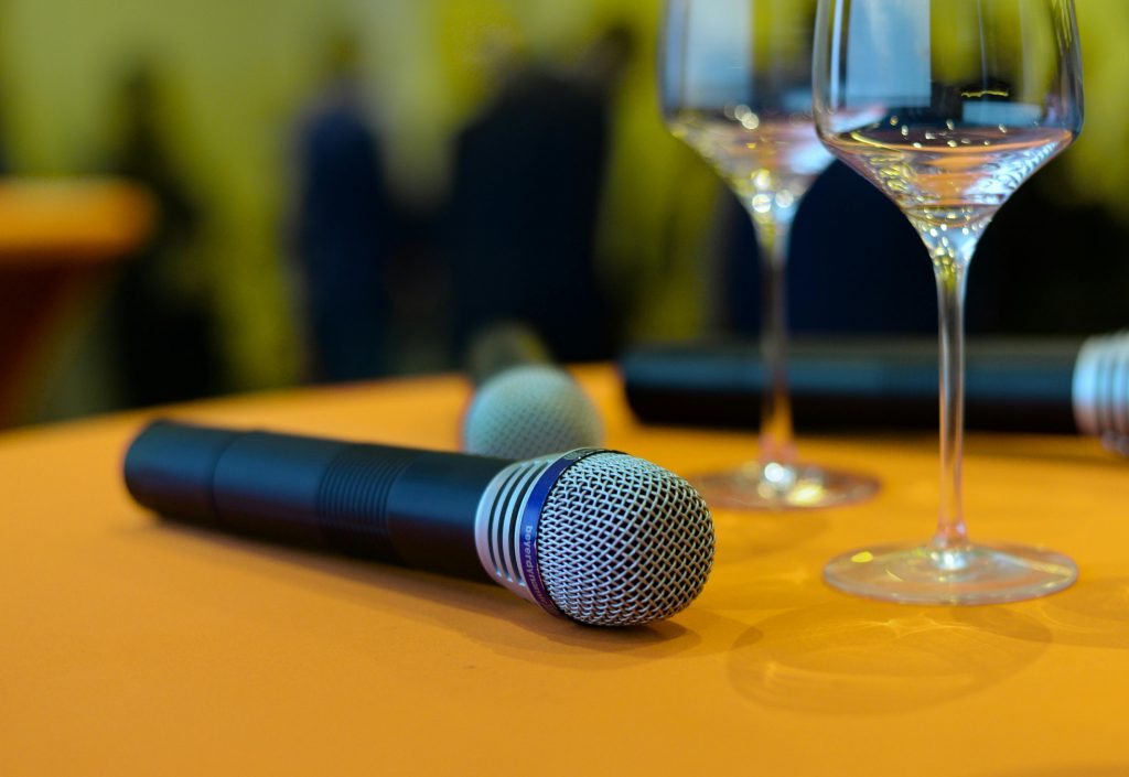 Close-up of microphones and wine glasses on an orange table, ideal for events or entertainment themes.